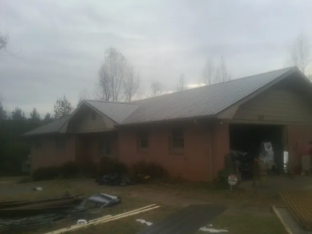 Gray metal roof on a stucco house with an attached garage in Victor