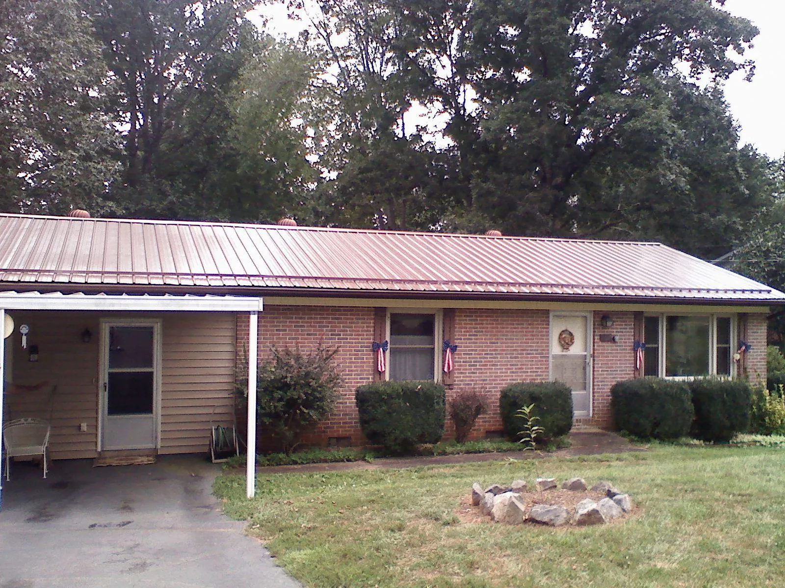 Bronze metal roof and carport on a brick ranch home — Roof Repair work by our crew in Victor